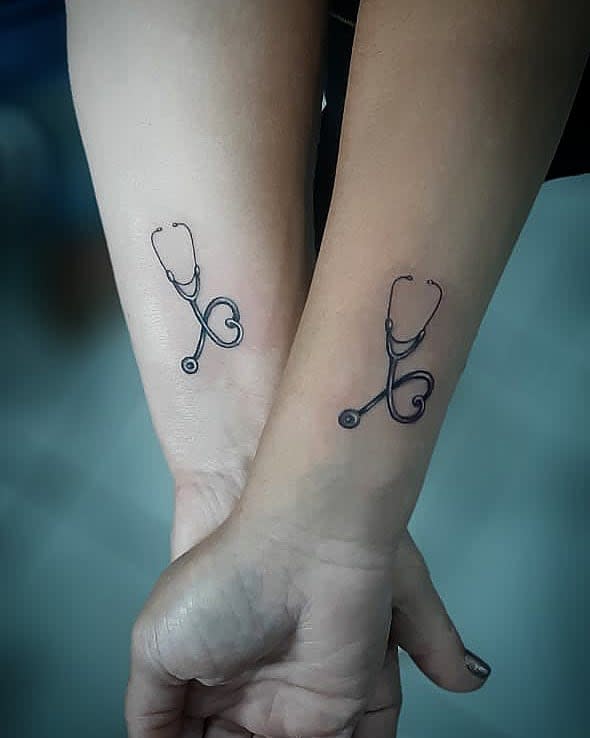 Matching stethoscope tattoos on the inner forearms