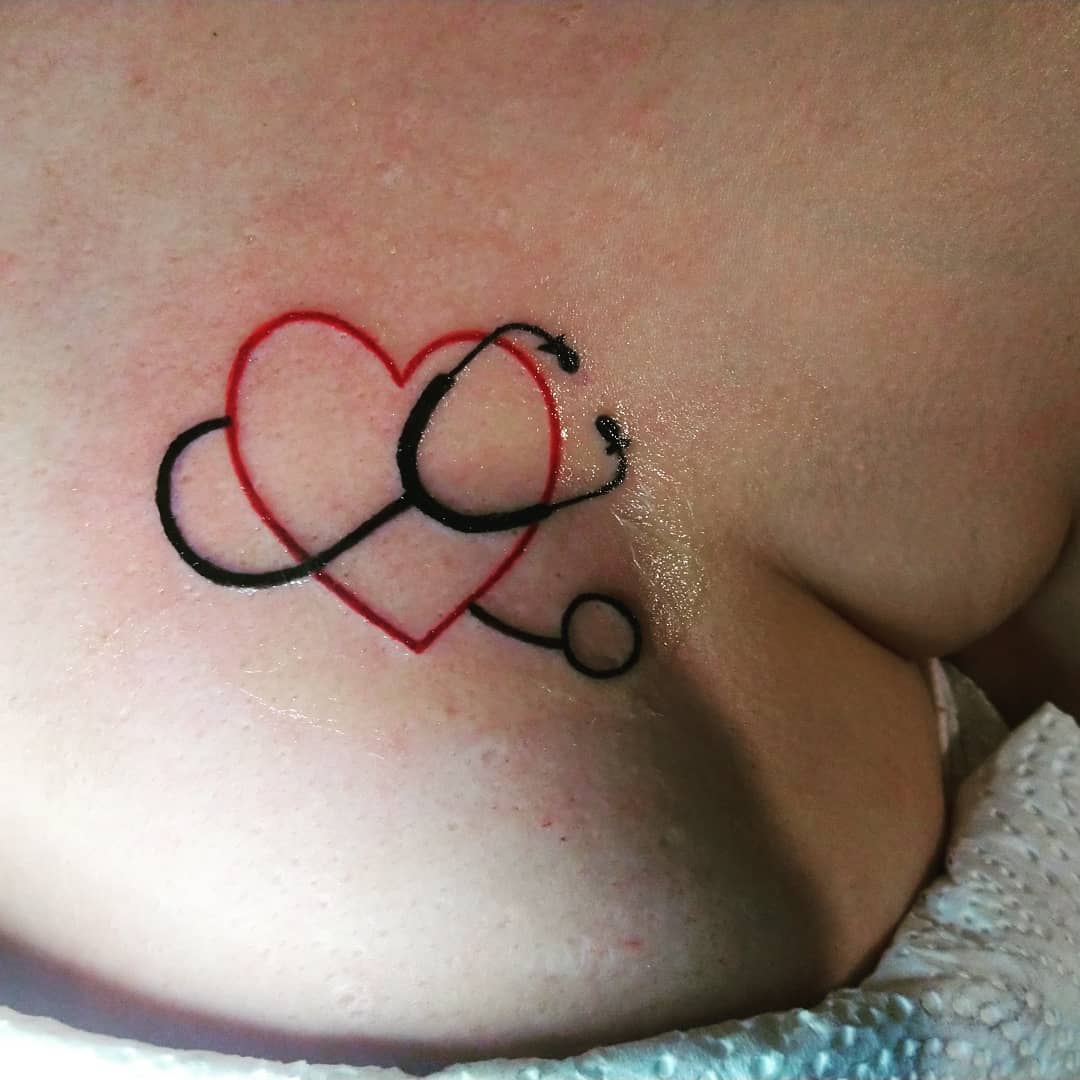 Tattoo of a stethoscope intertwined with a red heart on a chest