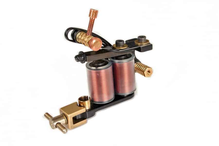 A tattoo machine with copper coils and brass components, designed for precision with a single needle, on a white background