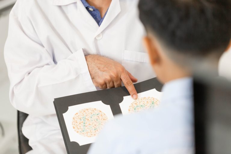 A doctor explains cataract surgery lens choices and shows a color blindness test to a patient