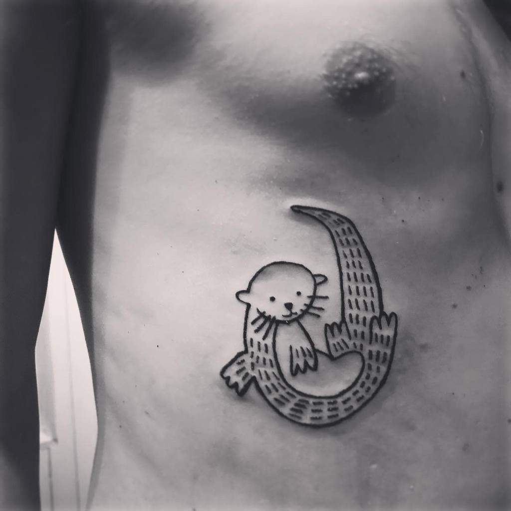A simple black tattoo of an otter on a person's side, with the playful otter curled up and smiling