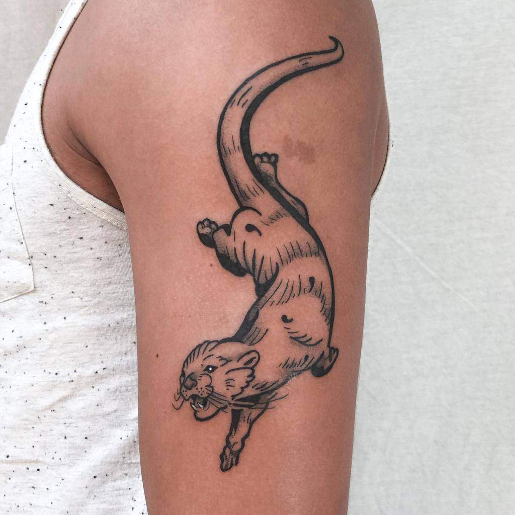 Bold black outline tattoo of a playful otter in motion, with intricate linework and dynamic pose on the upper arm