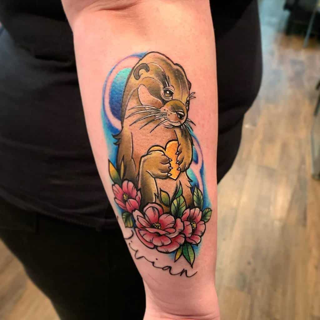 Forearm tattoo of an otter holding a heart, surrounded by pink flowers and blue accents