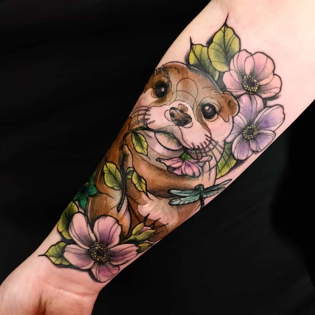 Forearm tattoo of an otter with purple flowers, green leaves, and a dragonfly