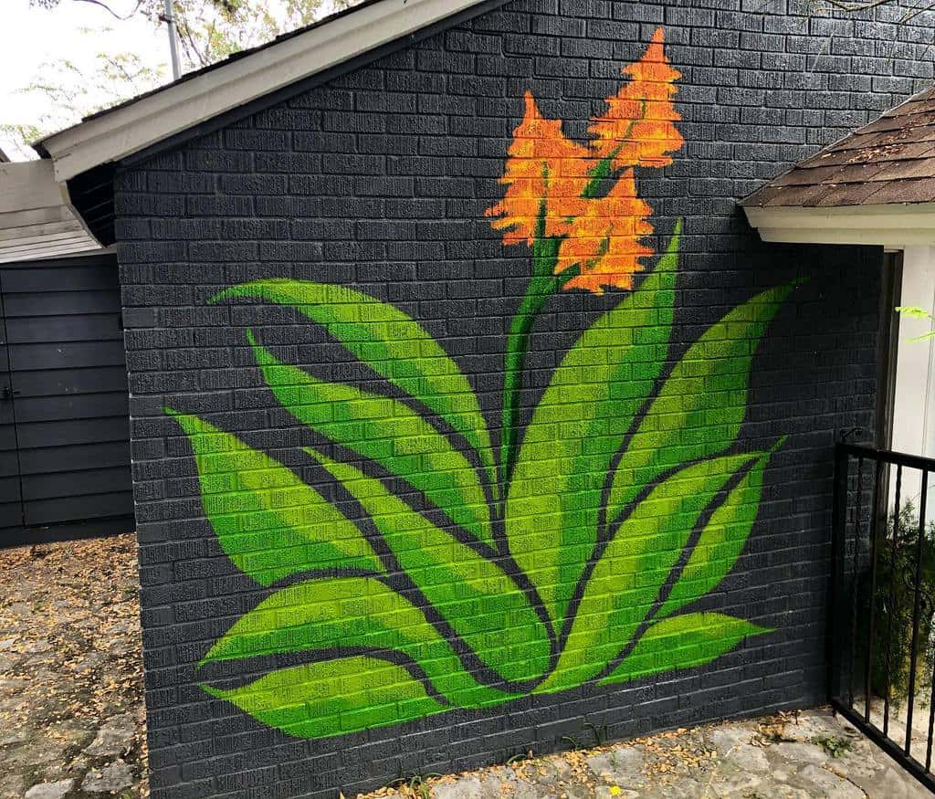 flower mural on black brick wall in garden