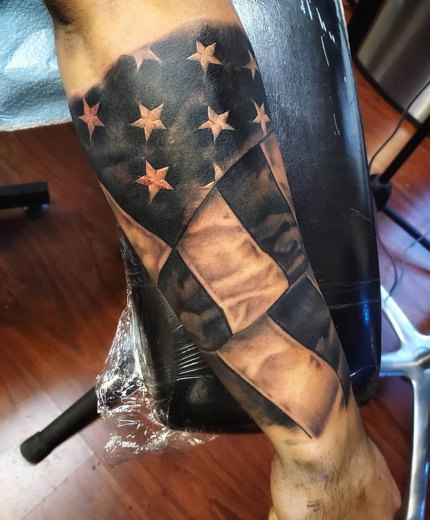 Outer forearm tattoo of an American flag design with realistic grey shading