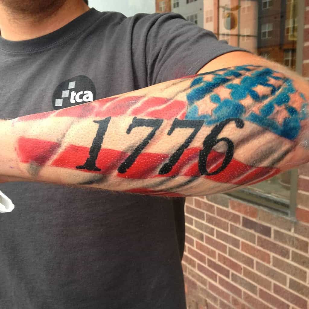 Tattoo featuring "1776" with an American flag design elegantly wrapped around the outer forearm