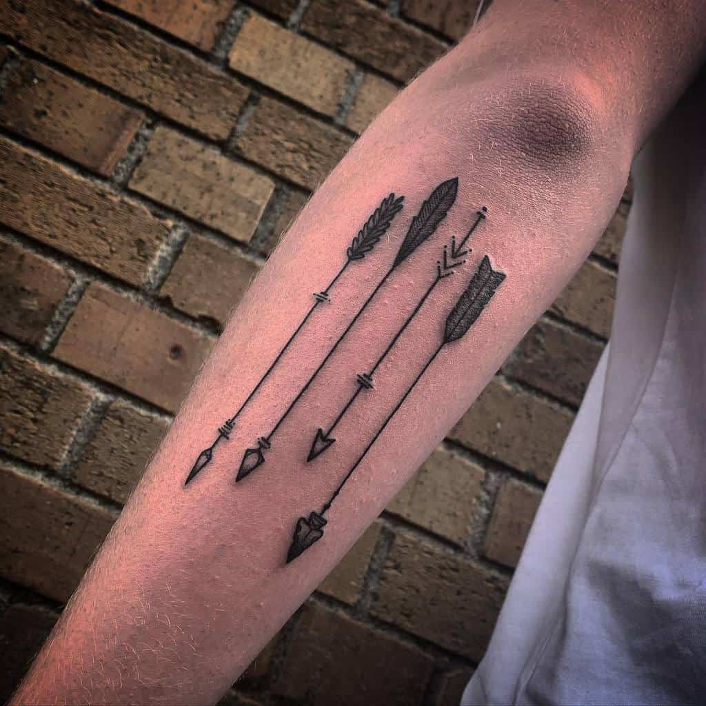 Outer forearm tattoo featuring four decorative arrows elegantly pointing downward