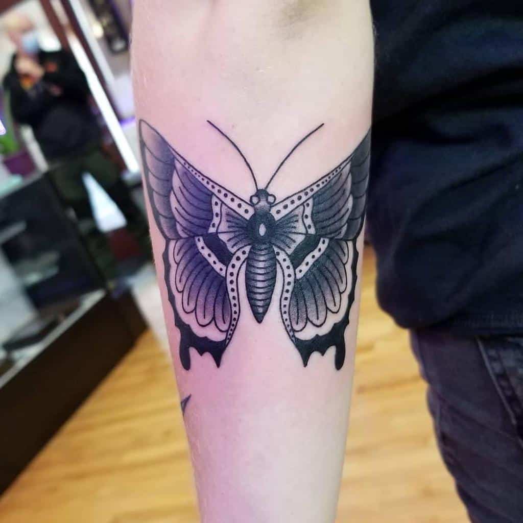 Black and gray butterfly tattoo elegantly adorning the outer forearm