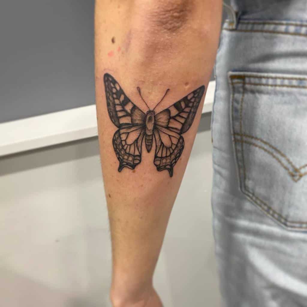 Black butterfly tattoo gracing the outer forearm