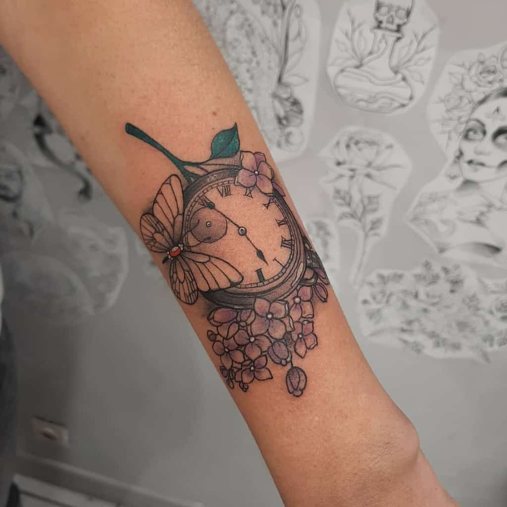 Outer forearm tattoo featuring a clock surrounded by butterflies and flowers, intricately designed in black and gray ink