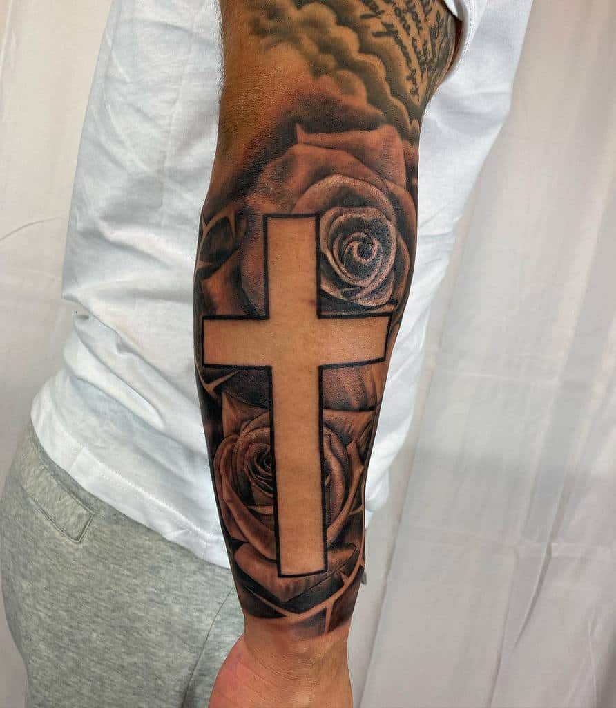 An outer forearm tattoo featuring a bold cross encircled by intricately detailed roses