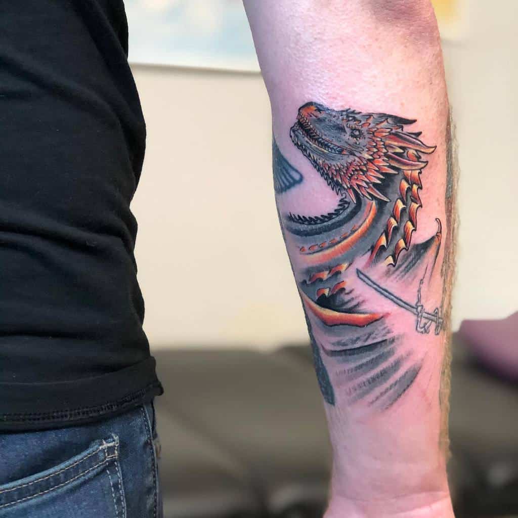 Forearm tattoo of a detailed dragon entwined with a sword