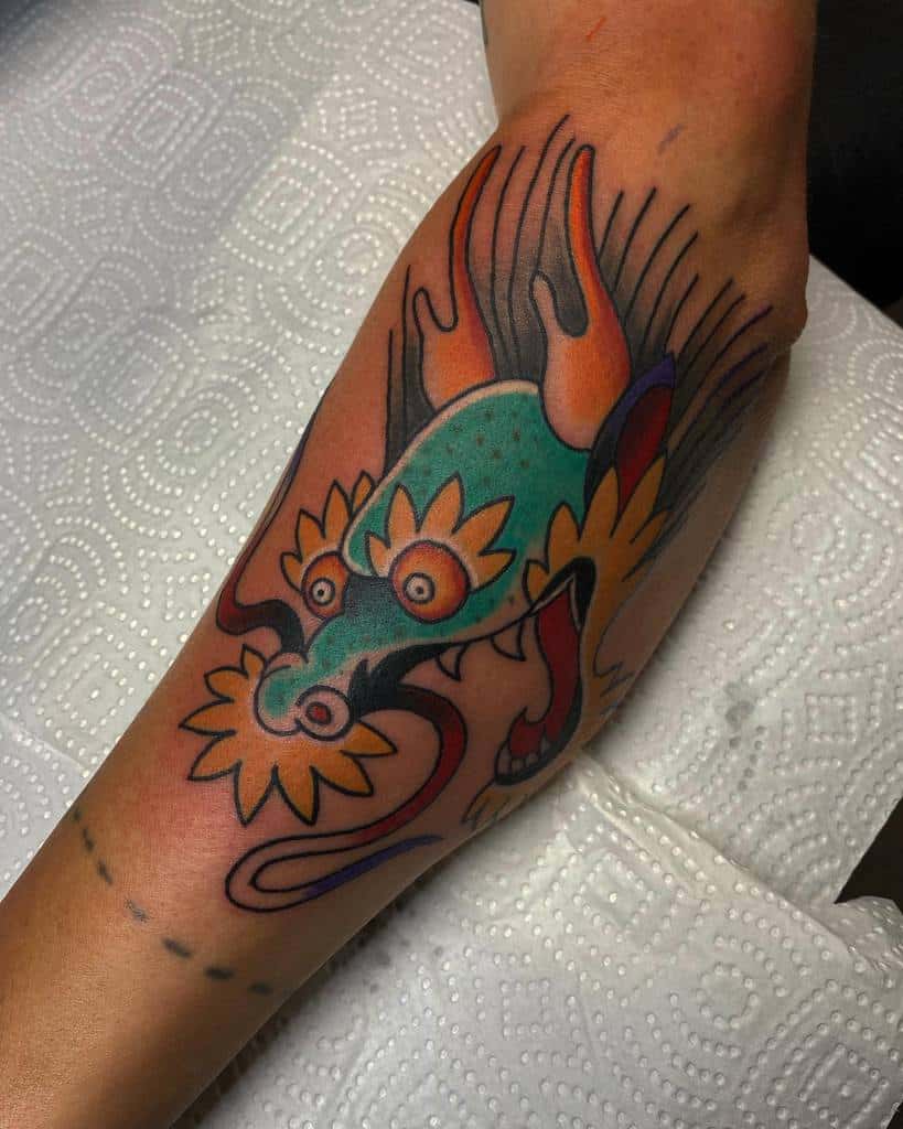 A colorful dragon tattoo with flowers beautifully adorns the outer forearm