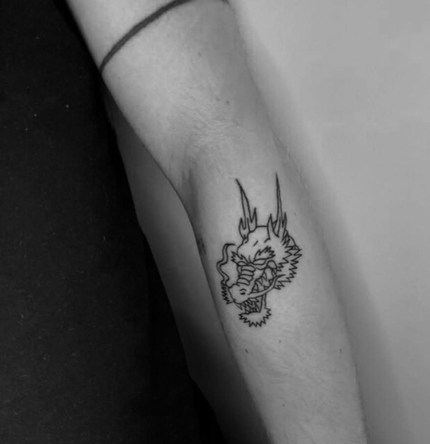 Black outline dragon tattoo on outer forearm