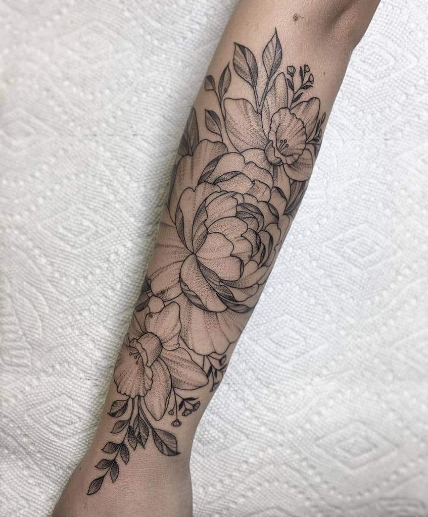 Intricate floral tattoo design graces the outer forearm, adorned with delicate leaves and budding blooms