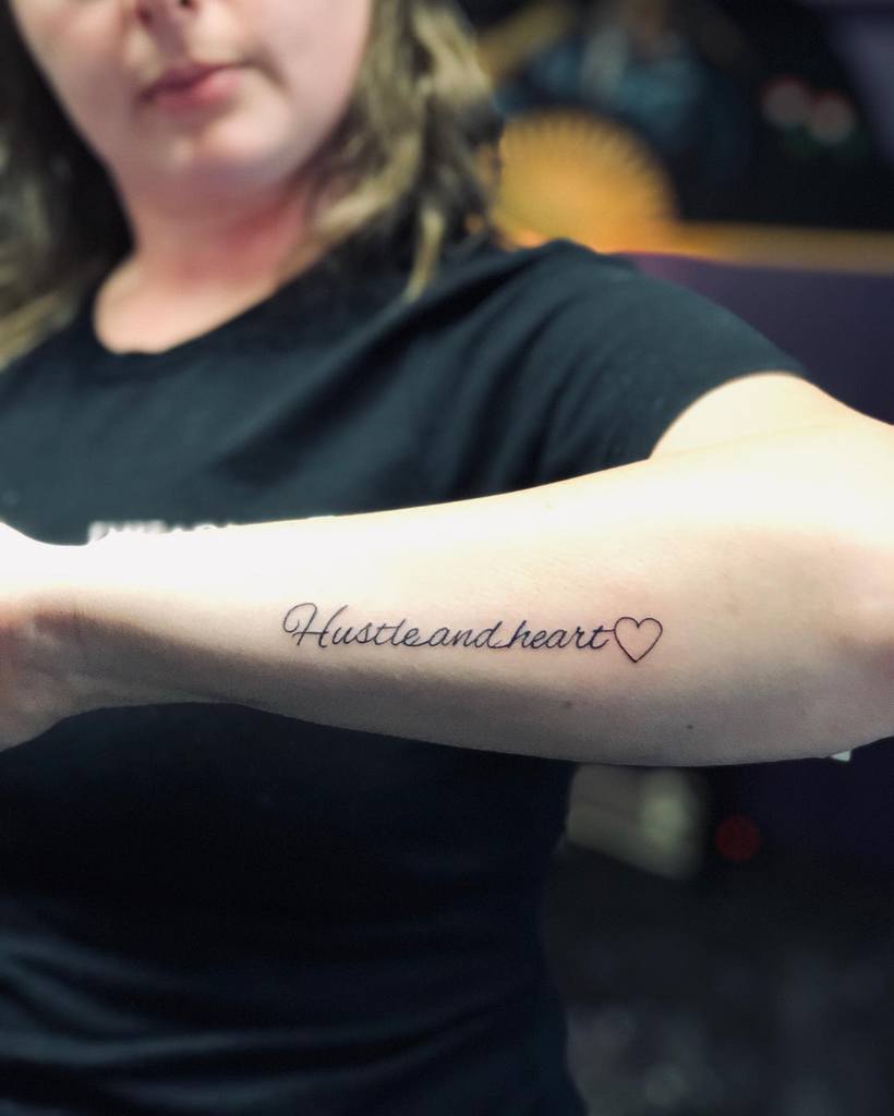 Outer forearm tattoo featuring the words "Hustle and heart" alongside a heart symbol
