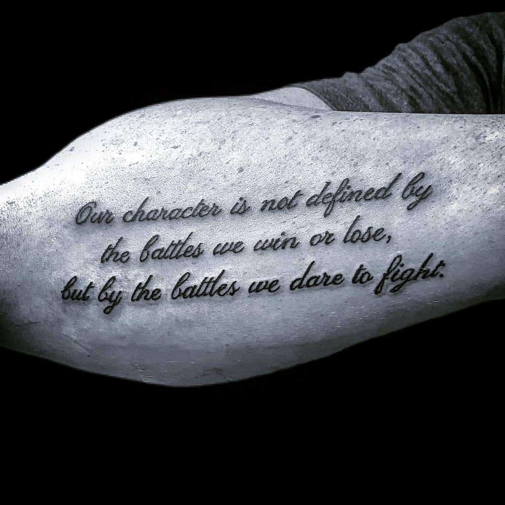 Tattooed outer forearm showcasing a motivational quote in elegant cursive script