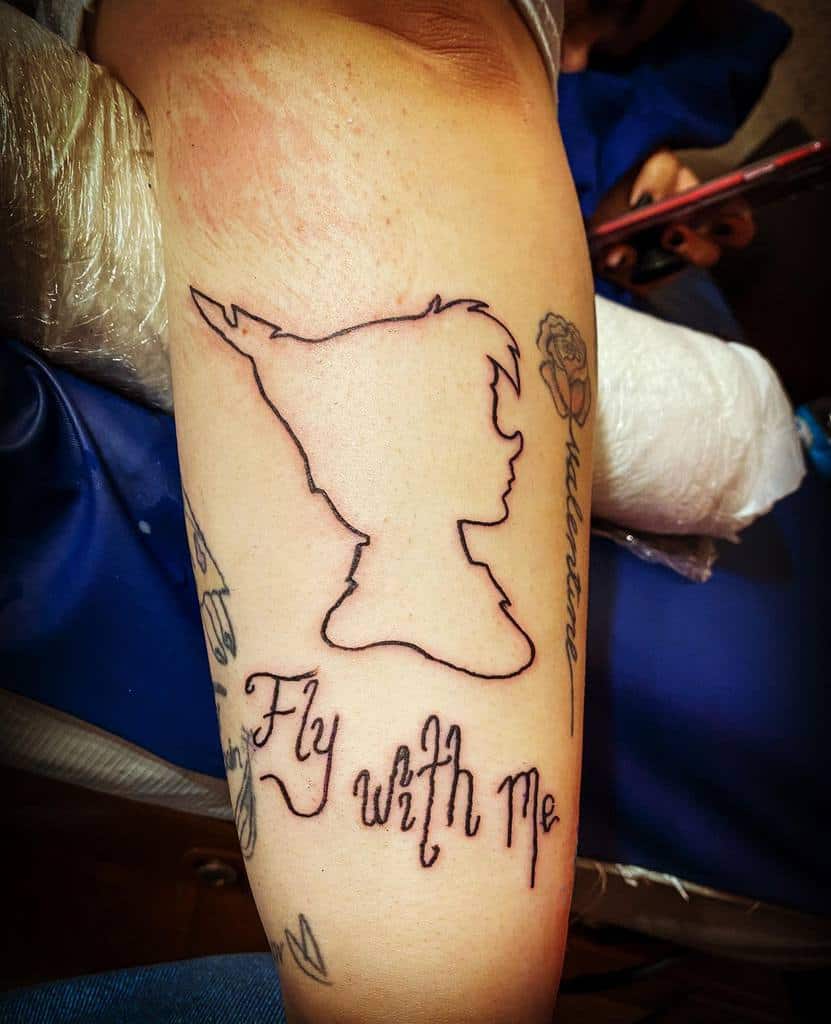 Minimalist line-art tattoo of Peter Pan’s silhouette with the phrase "Fly with Me" in whimsical script