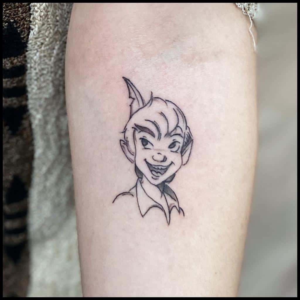 Fine-line tattoo of Peter Pan's face with a playful grin, featuring delicate black ink details