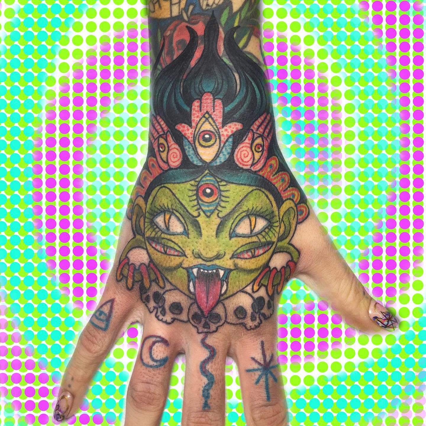 Hand adorned with a colorful frog tattoo on the back, against a psychedelic background