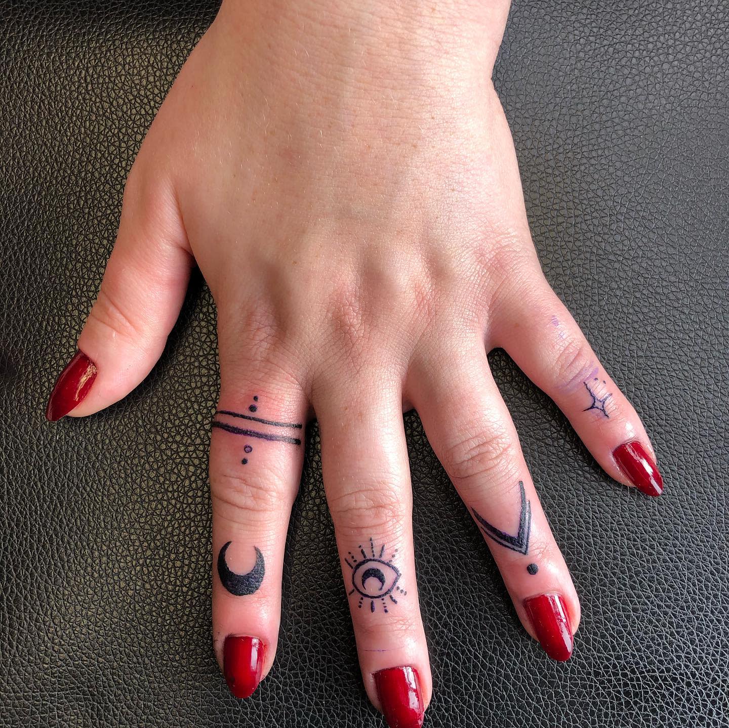 Tattoos of small Pagan black symbols on fingers