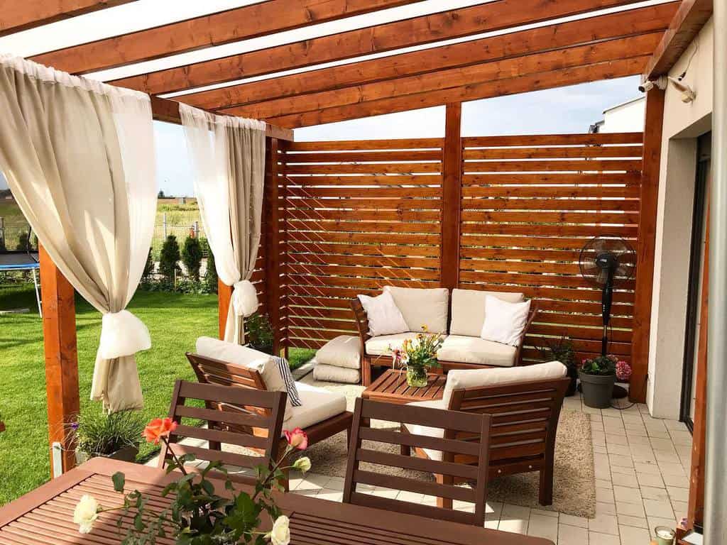 small stone paver patio with pergola and wood furniture 