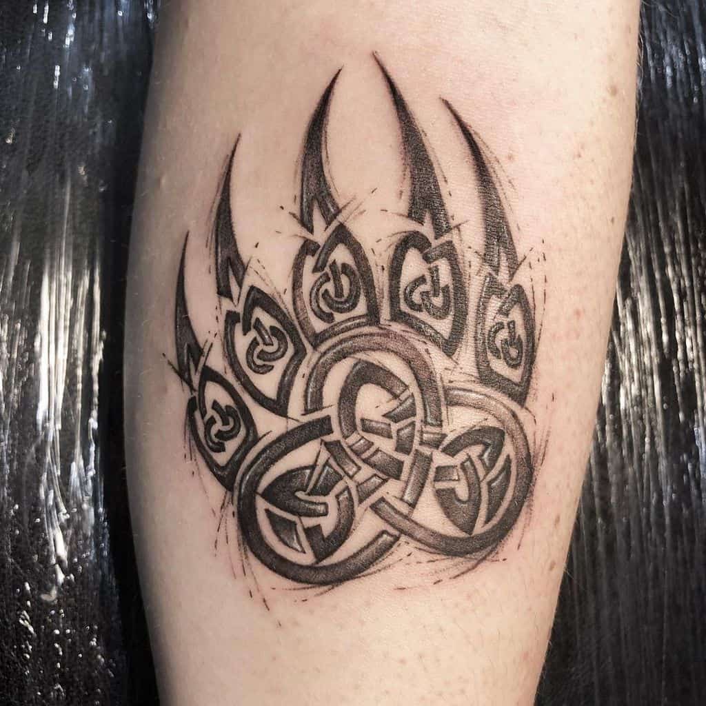 Tattoo of a majestic bear paw with intricate Celtic knot design in black ink on the forearm
