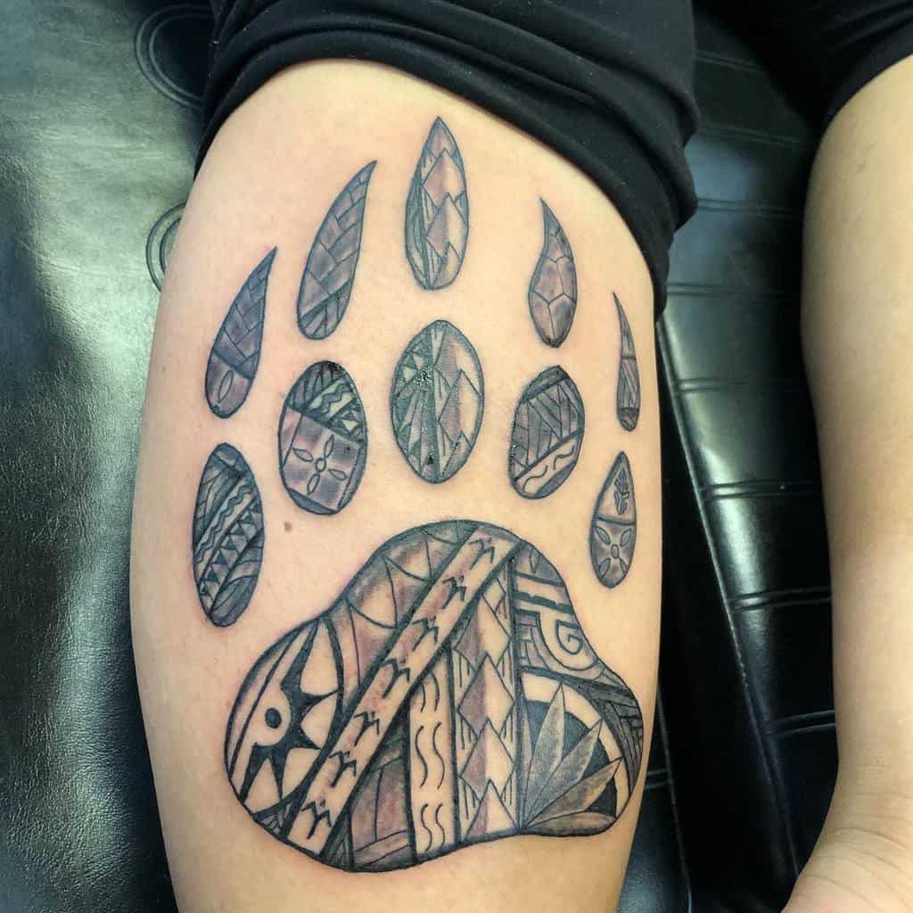 Tattoo of a stylized bear paw with Polynesian tribal patterns on an arm, capturing the spirit and strength of the majestic bear