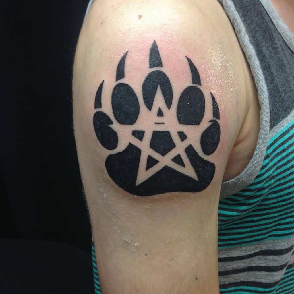 A striking tattoo of a bear paw print adorned with a star and pentagram graces the upper arm