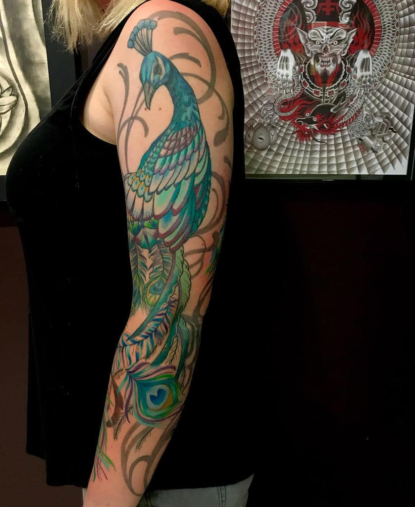 A colorful peacock tattoo on a woman's arm