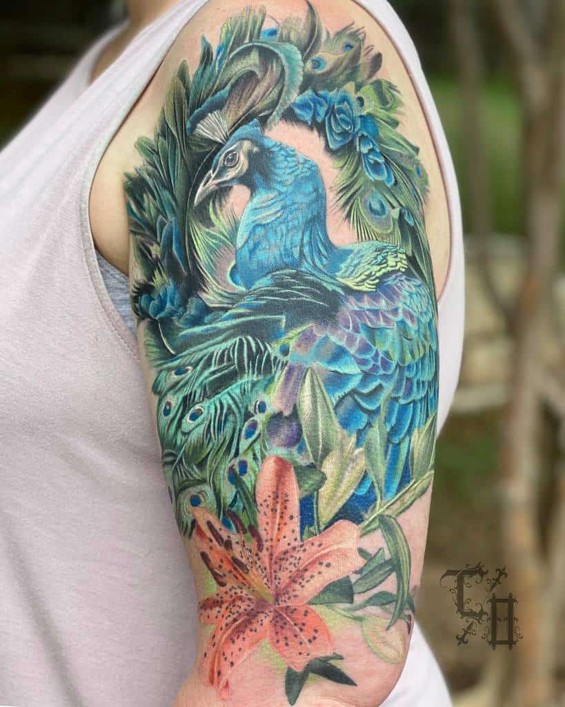 Colorful peacock tattoo with a flower on a woman's upper arm
