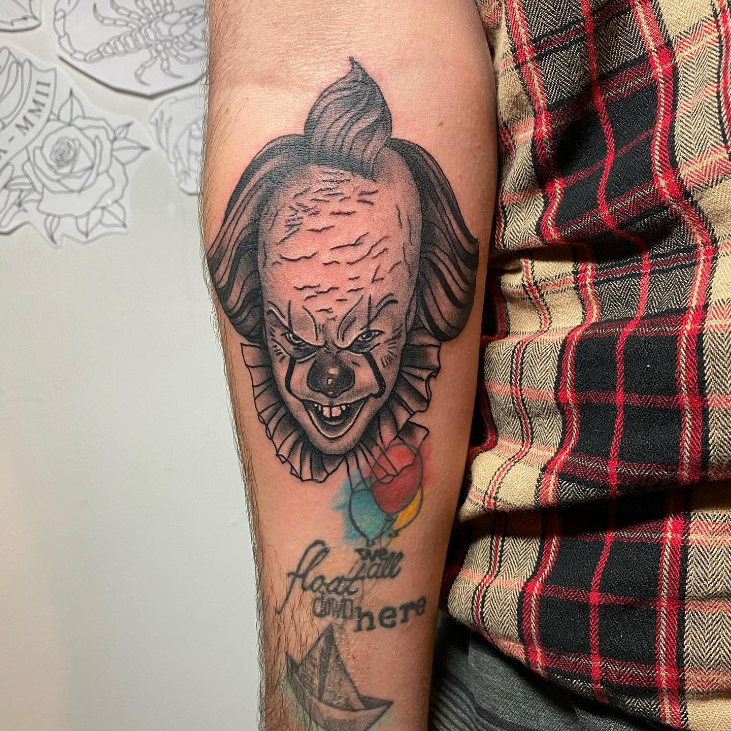 Pennywise tattoo on forearm with detailed shading, paired with colorful balloons and 'we all float' text