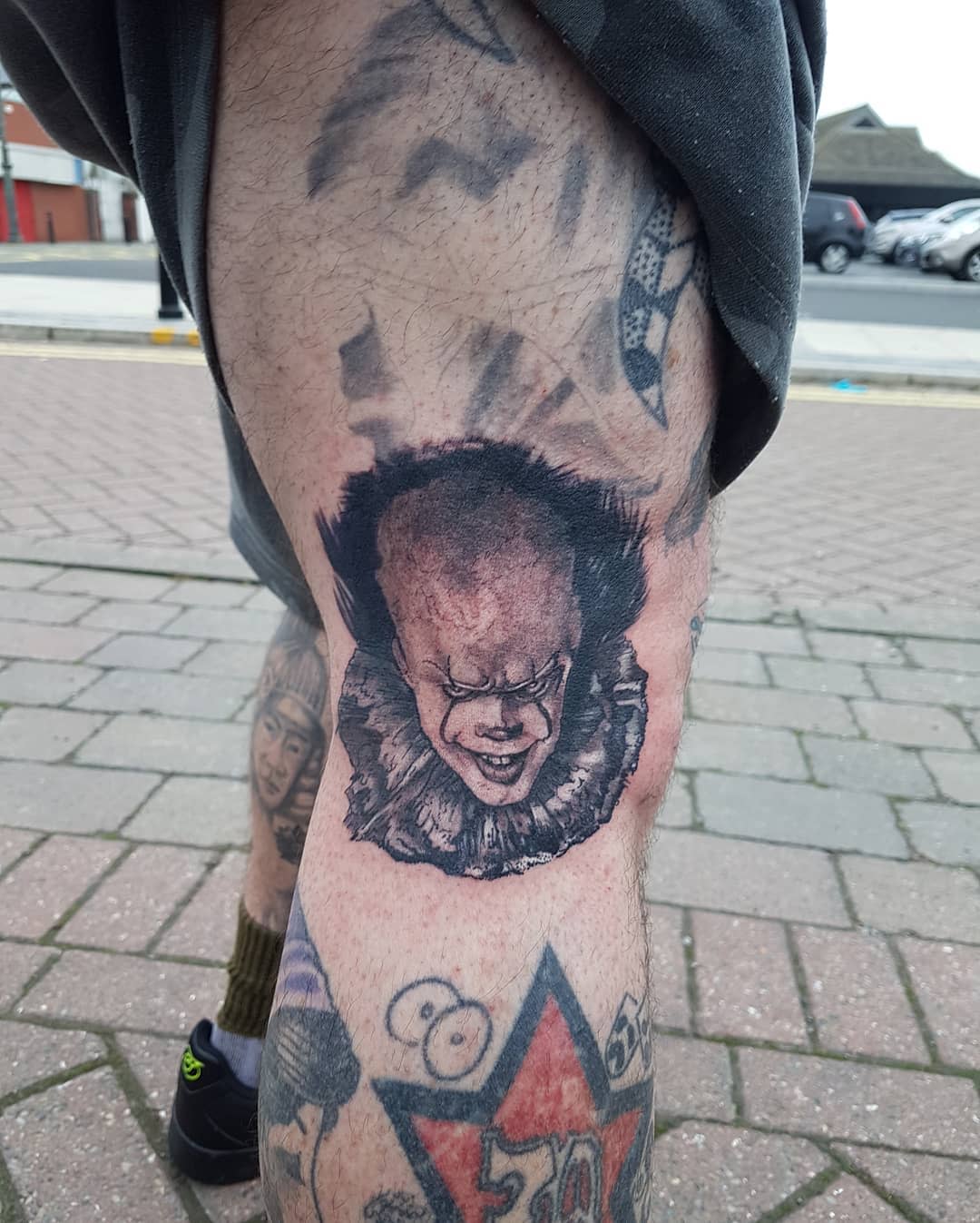 Small Pennywise tattoo on leg, featuring dark, shadowy shading and a menacing expression
