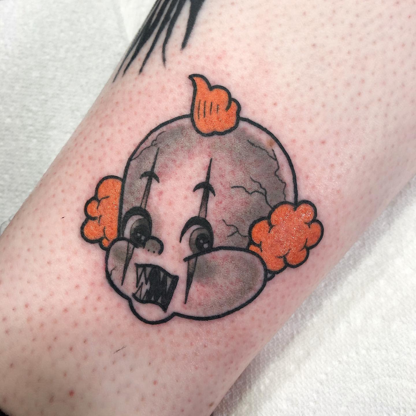 A traditional-style Pennywise tattoo with a cartoonish design on the lower leg