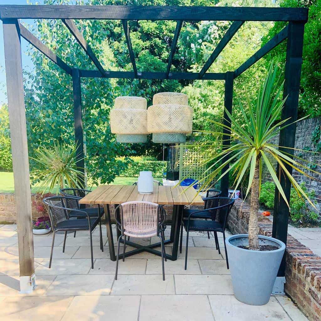 large paver patio black gazebo wood table black chairs potted plants