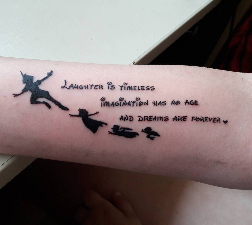 Tattoo of Peter Pan, Wendy, and Tinker Bell in flight with the quote 'Laughter is timeless, imagination has no age, and dreams are forever'