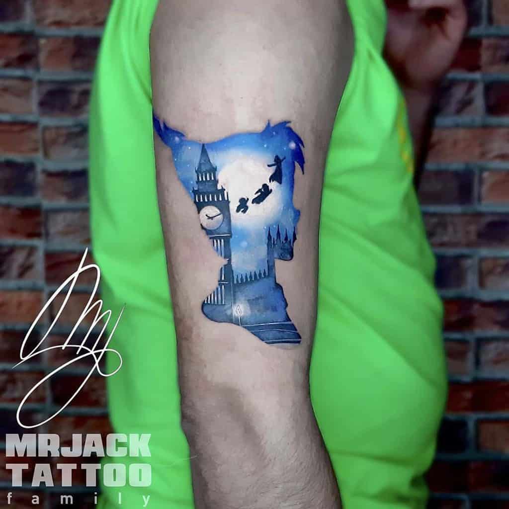 Peter Pan, Wendy, and brothers flying over Big Ben in a watercolor-style tattoo with a dreamy night sky