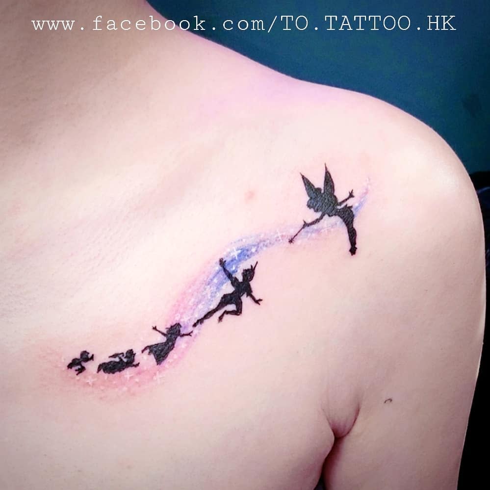 Peter Pan, Wendy, and Tinker Bell flying with a colorful pixie dust trail in a delicate shoulder tattoo