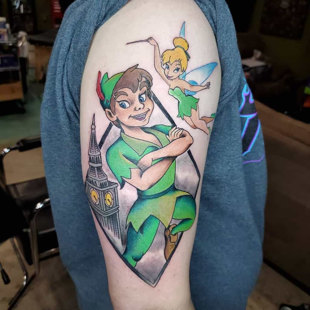 Colorful tattoo of Peter Pan with arms crossed, Tinker Bell flying above, and Big Ben in the background, framed in a geometric design
