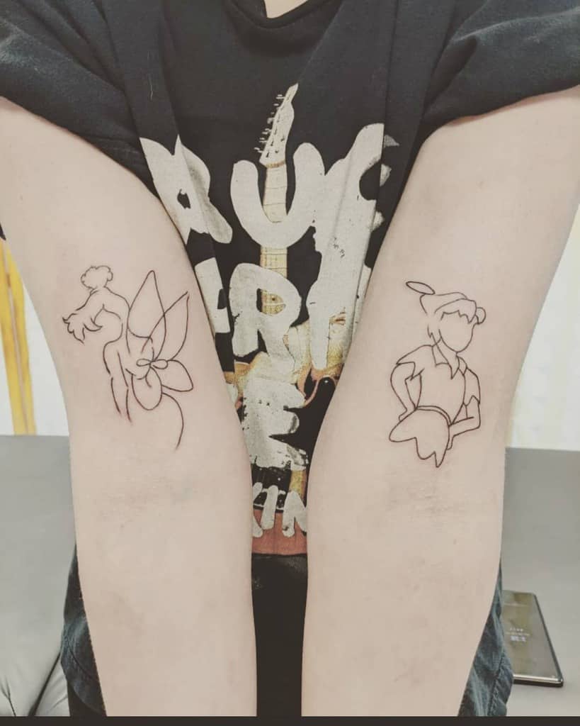 Matching minimalist line-art tattoos of Peter Pan and Tinker Bell, inked on opposite forearms, capturing a playful and whimsical connection