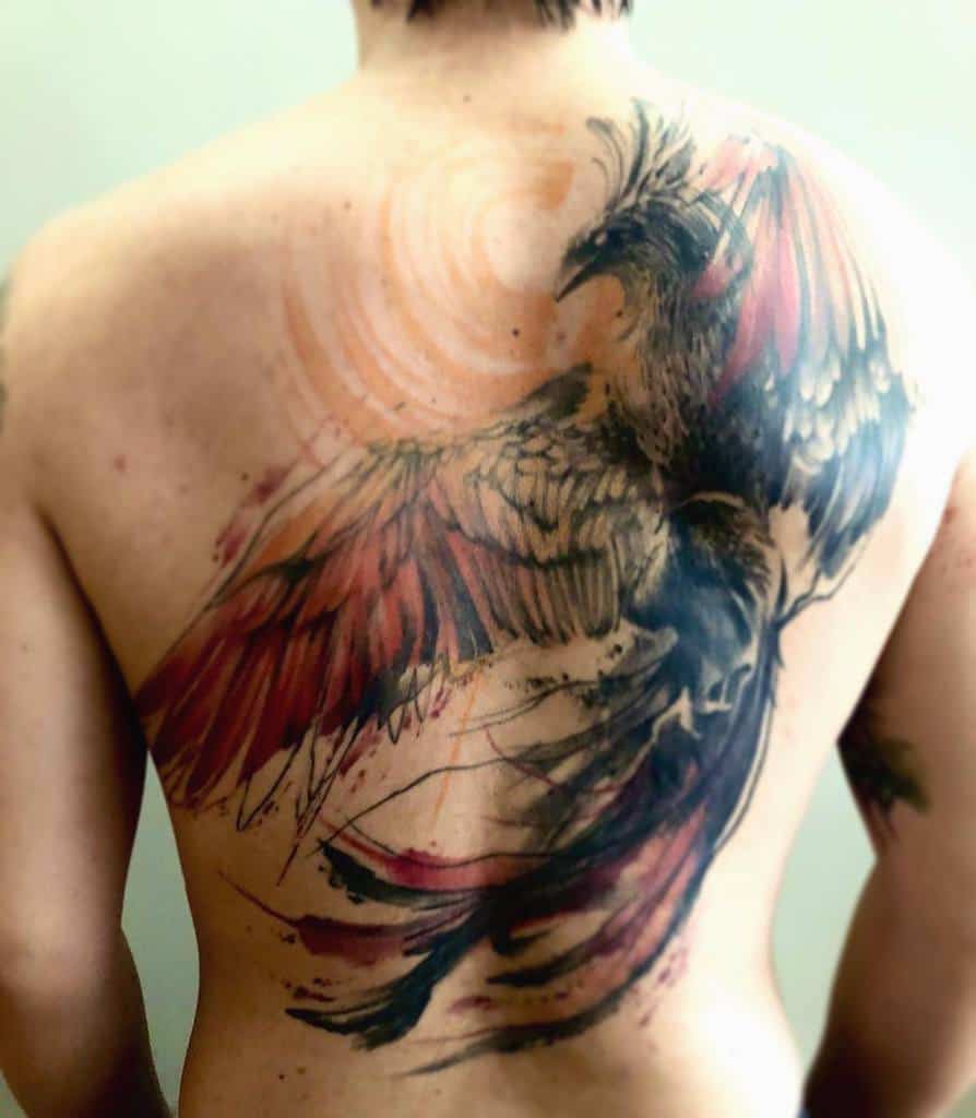Person with a large, colorful phoenix rising tattoo covering their entire back