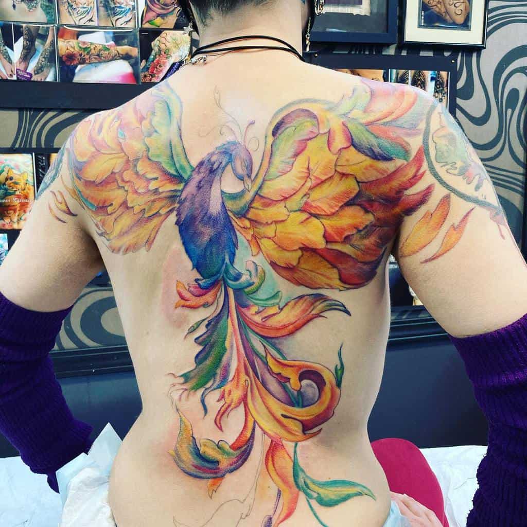 Back tattoo of a vibrant, colorful phoenix with outstretched wings