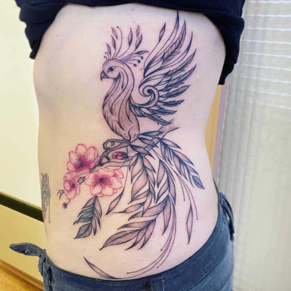 Side tattoo of a phoenix rising with floral elements on a person's torso