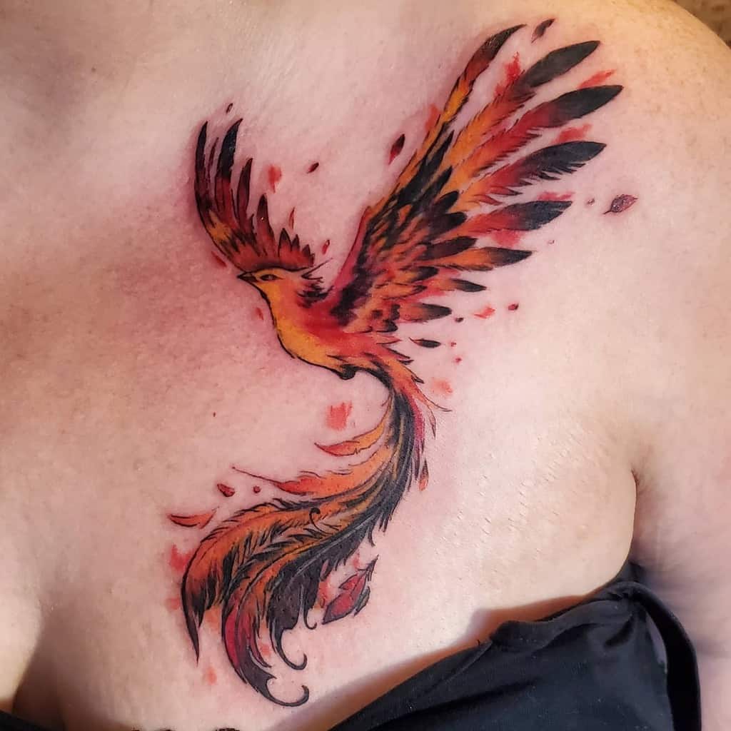 A vibrant phoenix rising tattoo with outstretched wings adorns a chest