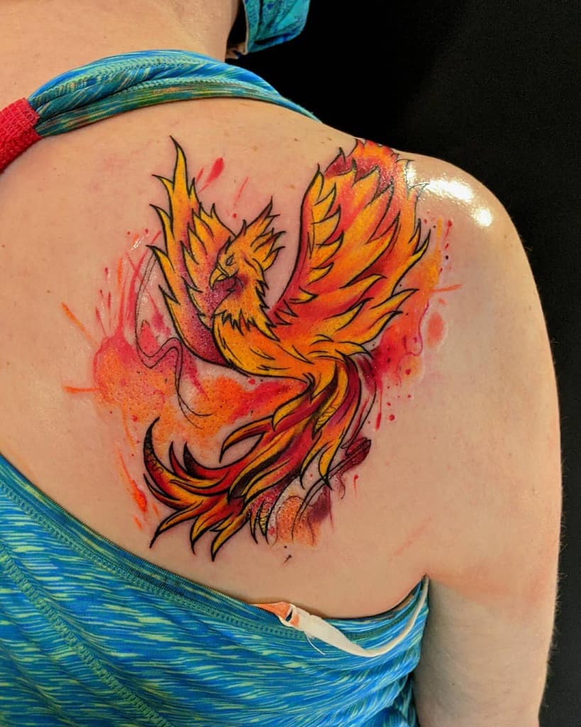 Vibrant phoenix rising tattoo with fiery colors on a person's shoulder