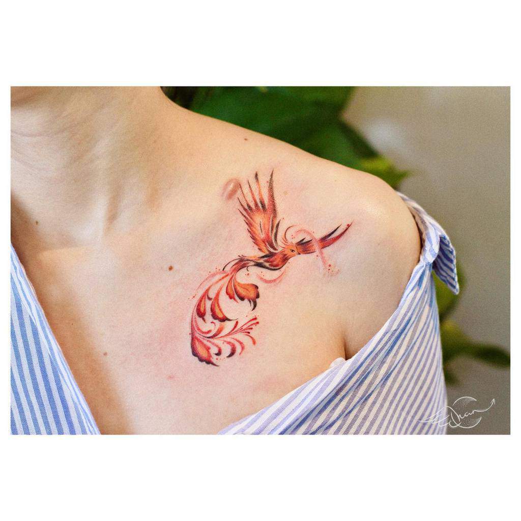 A colorful phoenix rising tattoo on a person's shoulder