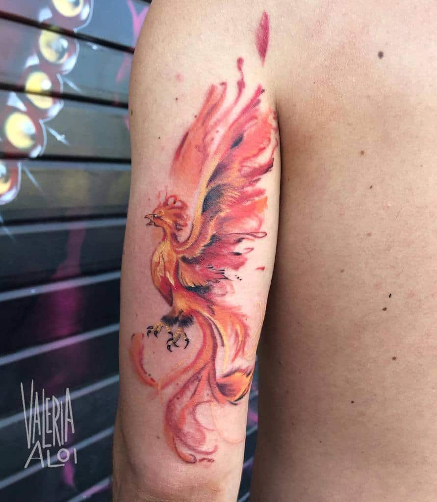 Tattoo of a fiery phoenix rising on a person's upper arm