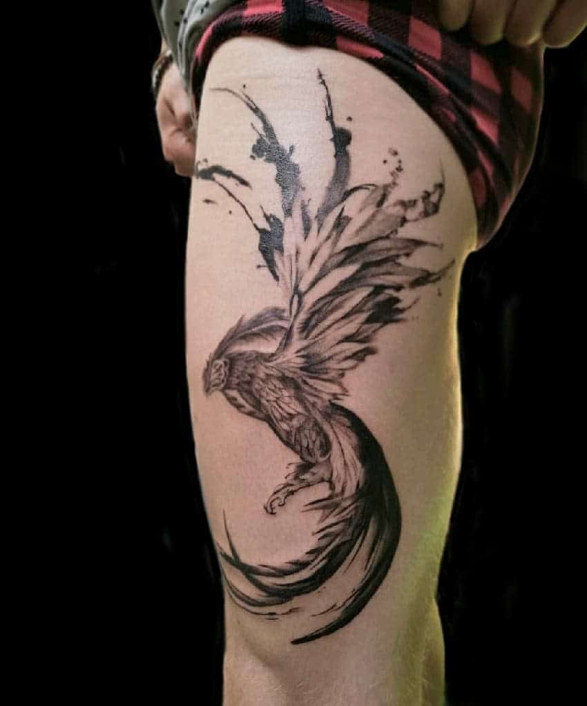 Black ink phoenix rising tattoo with a sweeping tail on an upper thigh