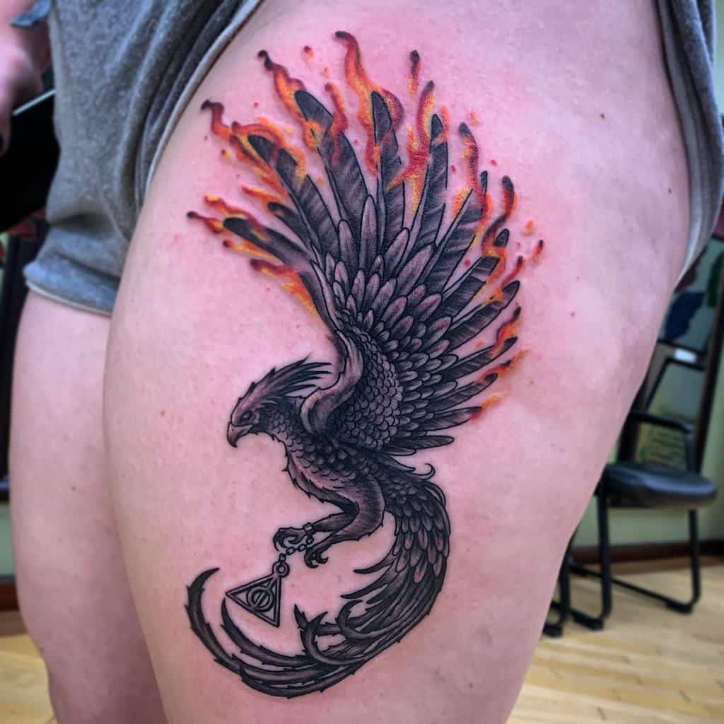 A fiery phoenix rising with outstretched wings adorns a person's thigh